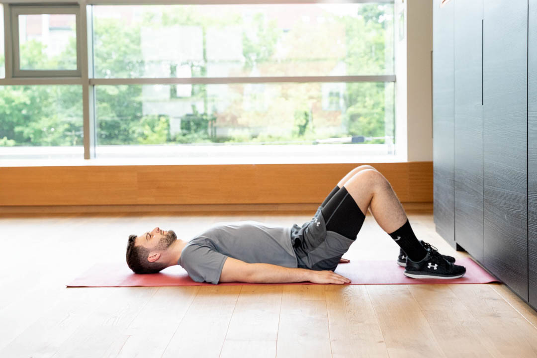 Mann der mit angewinkelten Beinen auf dem Boden liegt
